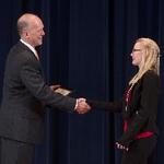 Doctor Potteiger shaking hands with an award recipient in a black blazer and red shirt